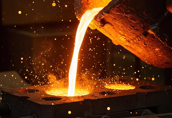 Molten metal pouring into a mold during foundry casting, supported by core drying and post-cast heat treatment ovens